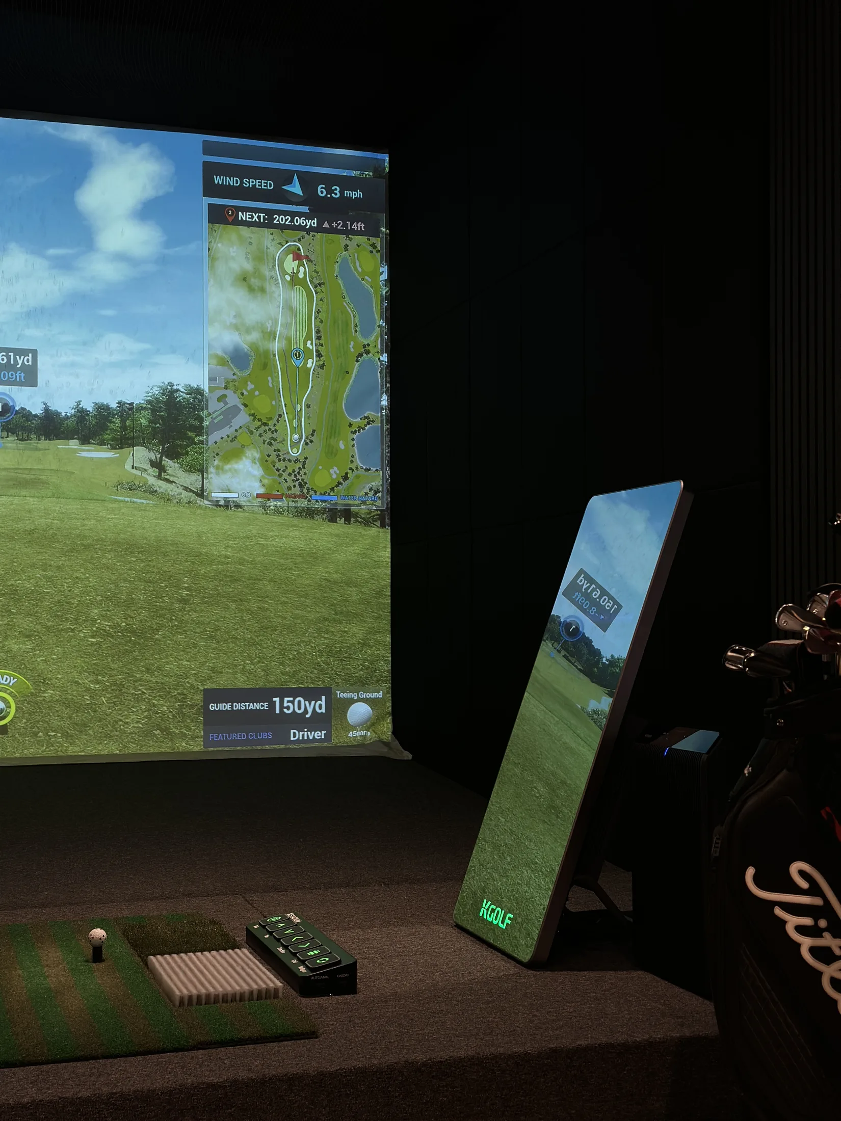 KStadium simulator bay with screen, touch mirror kiosk, and auto-tee controls