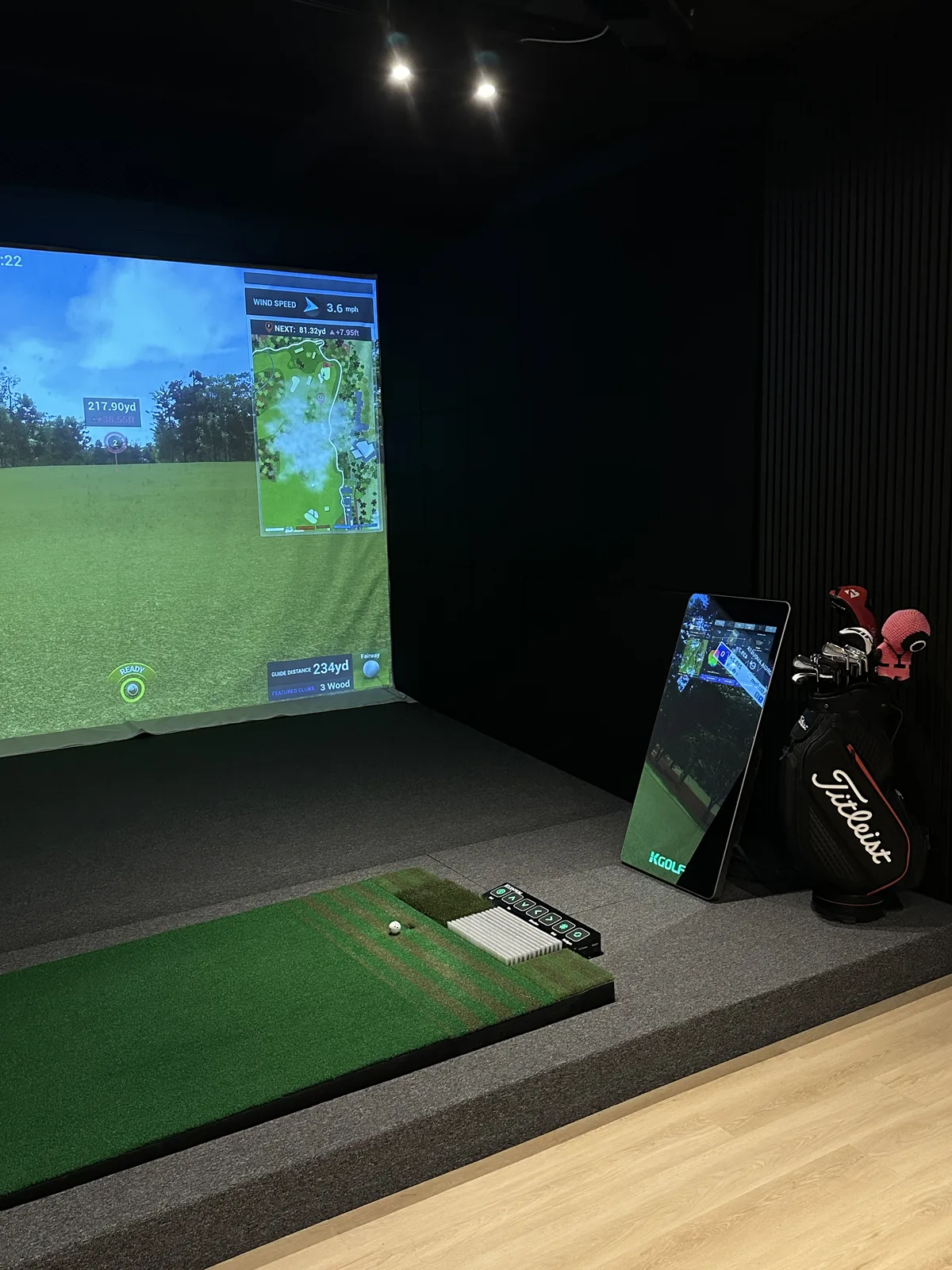 Simulator bay with touchscreen and golf clubs